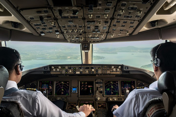 Wall Mural - Inside cockpit of commercial airplane while fly approaching the runway. Outside window can see beautiful light from airport and inside cockpit can see pilots flying airplane. Modern aviation concept.