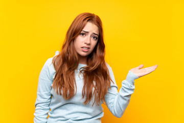 Wall Mural - Teenager redhead girl over isolated yellow background unhappy for not understand something