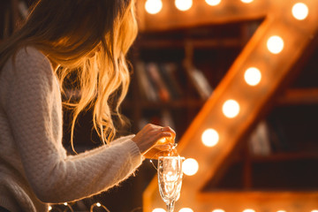 Wall Mural - girl decorates a glass of champagne with Christmas lights