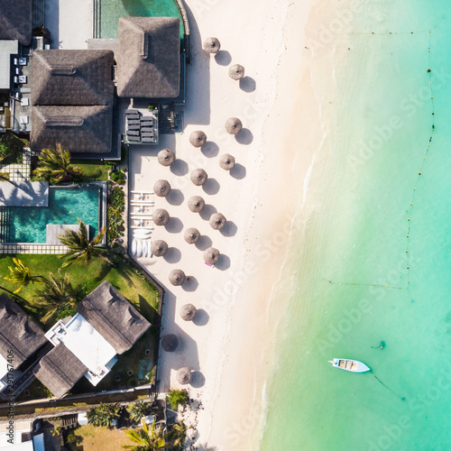 Cuadros en Lienzo Aerial view of beautiful tropical beach front hotel resort with swimming pool, palm leaves umbrellas and turquoise sea