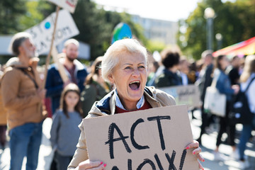 Wall Mural - Senior with placard and poster on global strike for climate change, shouting.