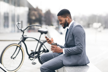 Handsome afro businessman texting on phone during coffee break