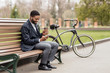 © Prostock-studio - Coffee break. Happy businessman using phone next to bike