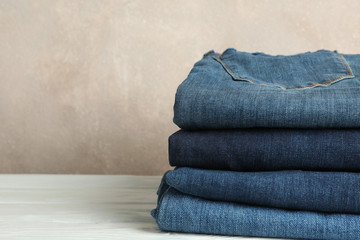 Wall Mural - Stack of jeans pants on white background, space for text