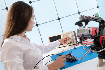 Wall Mural - A young woman writes an algorithm for the robot arm. Science Research Laboratory for Robotic Arm Model. Computer Laboratory