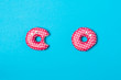 © Jaroslav Noska - Two pink donuts with white dots on blue background. One delicious donut. Donuts have eyes. View from above.