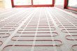 Electric underfloor heating red mats on cement floor. Heating red electrical cable on cement floor copy space background. Renovation and construction, comfortable warm home concept.