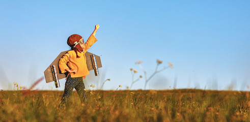 child pilot aviator with wings of airplane dreams of traveling in summer at sunset