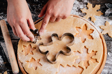 Christmas and New Year celebration traditions. Traditional festive food making, family culinary. Woman cutting cookies of raw gingerbread dough