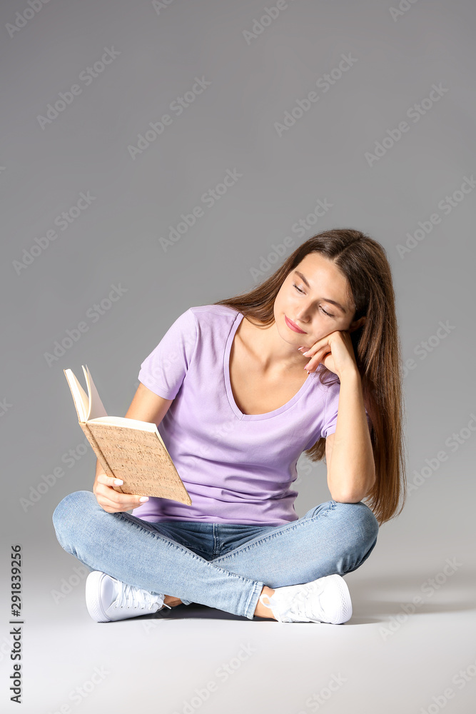Young girl with book on grey background