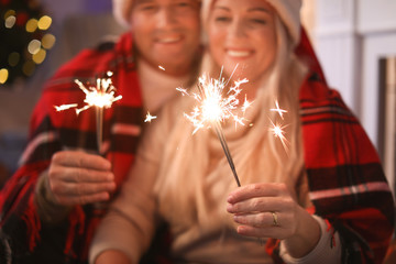 Wall Mural - Happy mature couple with Christmas sparklers at home