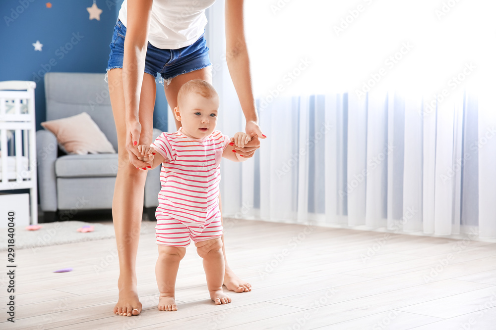 Mother teaching her little baby to walk at home