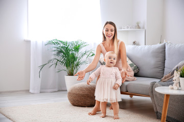 Sticker - Mother teaching her little baby to walk at home