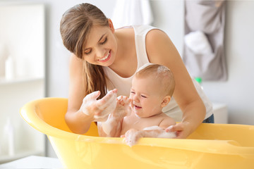 Mother bathing her cute little baby at home