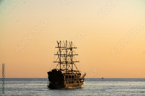 old pirate ship sailing at sea sunset