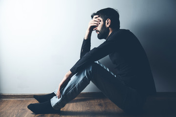 sad man sitting on ground on dark background