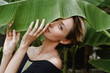 © Lyuba Burakova/Stocksy - Pretty woman holding banana leaf