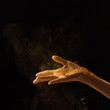 © Yaroslav Danylchenko/Stocksy - Gold dust falls on a female hand on a black background with copy space.