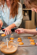 © rzcreative/Stocksy - A grandmother and her adult granddaughter placing and icing cookies on wax paper.