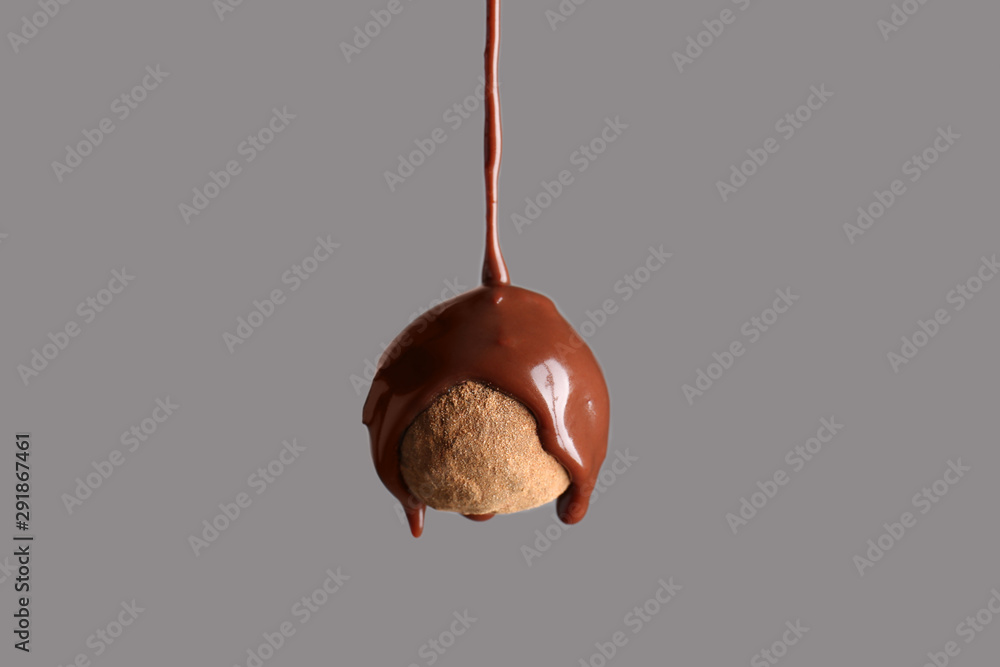 Pouring of chocolate on truffle candy against grey background