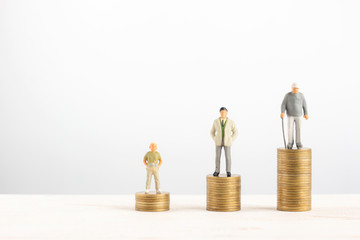 Old and young man stand on stacks of gold coins isolated on white background in Money pension retirement concept