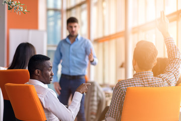 Young colleagues raising hands at the business meeting in office