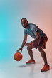 © Friends Stock - Ready to win. Full length of confident young african man in sports clothing playing basketball while standing against colorful background
