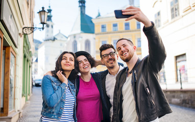 Wall Mural - A group of young friends standing outdoor in town, taking selfie.