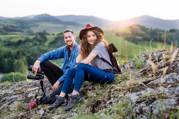 Wall Mural - young tourist couple travellers with binoculars hiking in nature, resting.