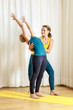 two women doing yoga one assists