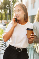 Sticker - Business lady with cup of coffee talking by mobile phone.