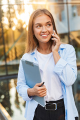 Sticker - Business lady with clipboard posing outdoors talking by mobile phone