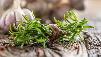 Wall Mural - Fresh rosemary and garlic cloves with spices on old wooden table