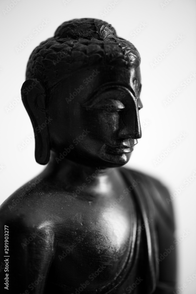 Sitting Buddha wearing colorful robes and having his legs crossed. His hands are pressed together in front of his body as a gesture of praying. This ... - obrazy, fototapety, plakaty 