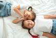 © Pixel-Shot - Portrait of cute twin girls lying on bed, top view