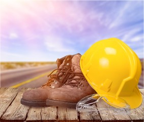 Wall Mural - Yellow working hard hat, goggles and work boots on  background