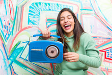 Young Pretty Woman With A Vintage Radio Against Graffiti Wall