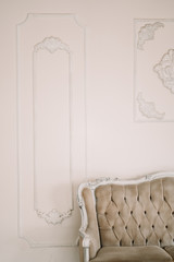 decorative clay stucco relief molding with ornaments on white ceiling in classical style interior with part of vintage sofa. nobody.