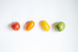 Red, green and yellow tomatoes in line on white background, flat view