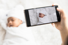Mother 's Hand Holding Smartphone Use To Taking Photo Cute Newborn Baby For Memories And Pose In Social Network.