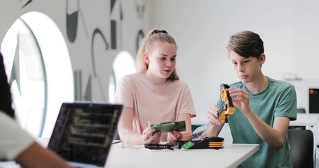 high school students working on a robotic arm in class