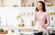 © Prostock-studio - Young woman cooking and talking on cellphone at kitchen