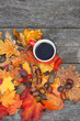 Autumn Background with tea cup and colourful leaves over wooden board. Thanksgiving wooden table with bright autumn leaves, cones, acorns. Autumn season concept, fall backdrop. copy space
