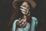 Fototapeta Boho - Boho chic woman in a straw hat in a white short blouse and with silver turquoise jewelry. Boho fashion. Hippie style, stylish girl with silver rings