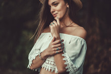 Beautiful Fashionable Boho Chic Woman In Straw Hat And In A White Short Blouse With Silver Turquoise Jewelry. Boho Fashion. Stylish Girl With Silver Rings Using Hippie Style.