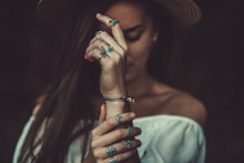 Boho Chic Woman In A Straw Hat In A White Short Blouse And With Silver Turquoise Jewelry. Boho Fashion. Stylish Girl With Silver Rings Using Hippie Style.