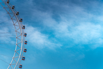 Small part of the Ferris wheel with blue sky on a background.