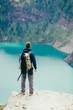 © Cavan Images - Hiker is standing on a cliff looking at the lake in GlacierNP, Montana