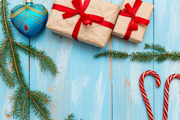 Fur spruce pine coniferous branches, gift box craft paper with red bow on the blue painted brushed wooden background