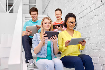 Wall Mural - education, technology and learning concept - group of happy international high school students or classmates with tablet pc computers sitting on stairs